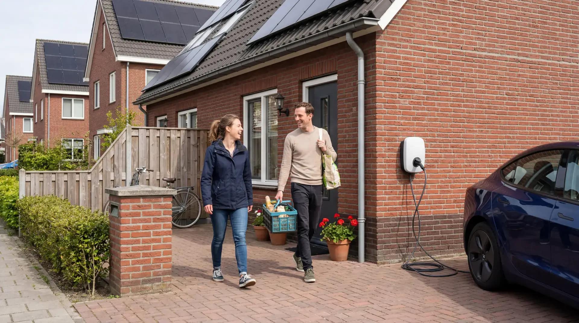 Elektrische auto aan laadpaal op Nederlandse oprit met zonnepanelen op het dak