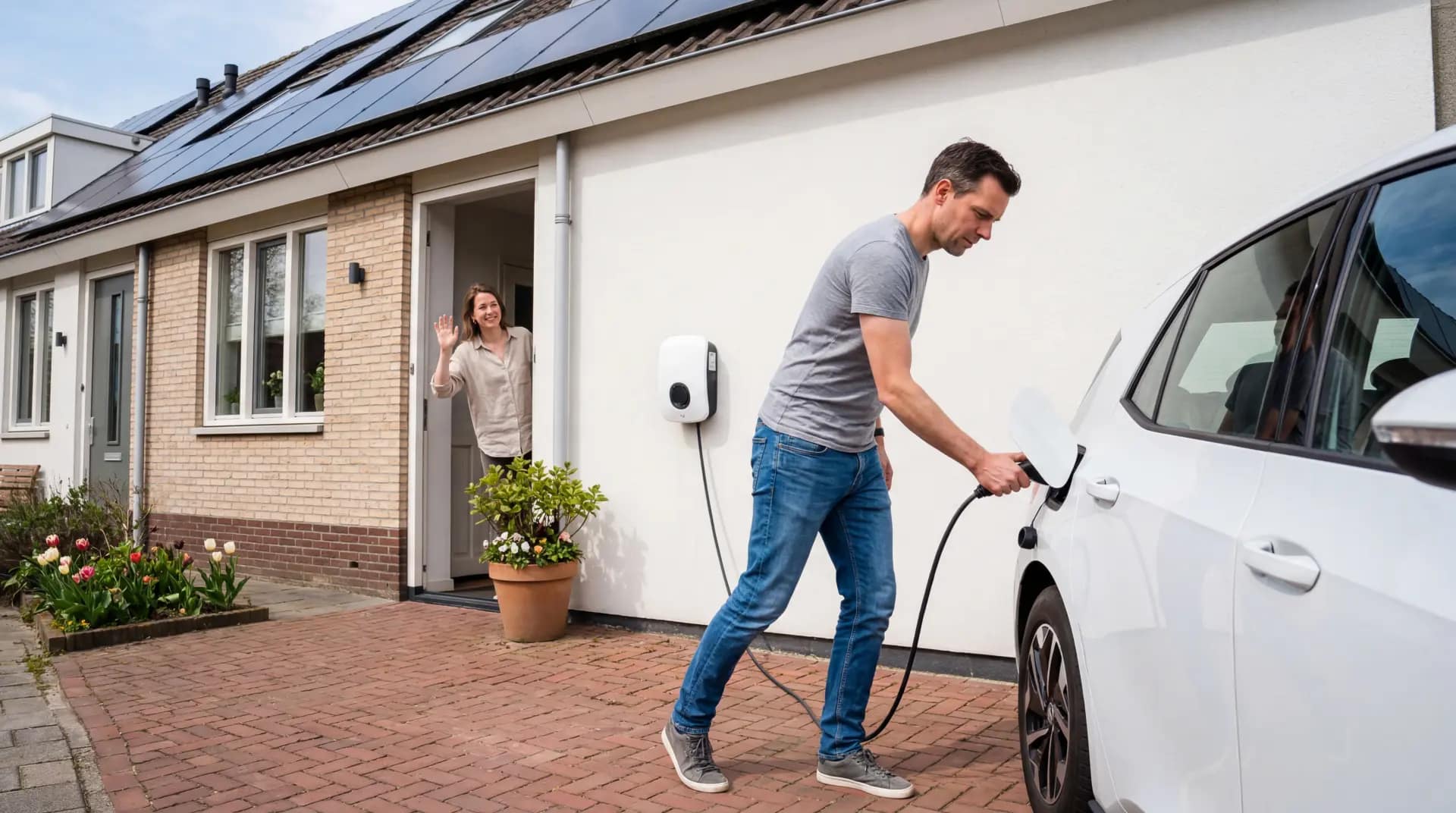 Easee Charge Up laadpaal gemonteerd op witte gevel naast oprit met elektrische auto