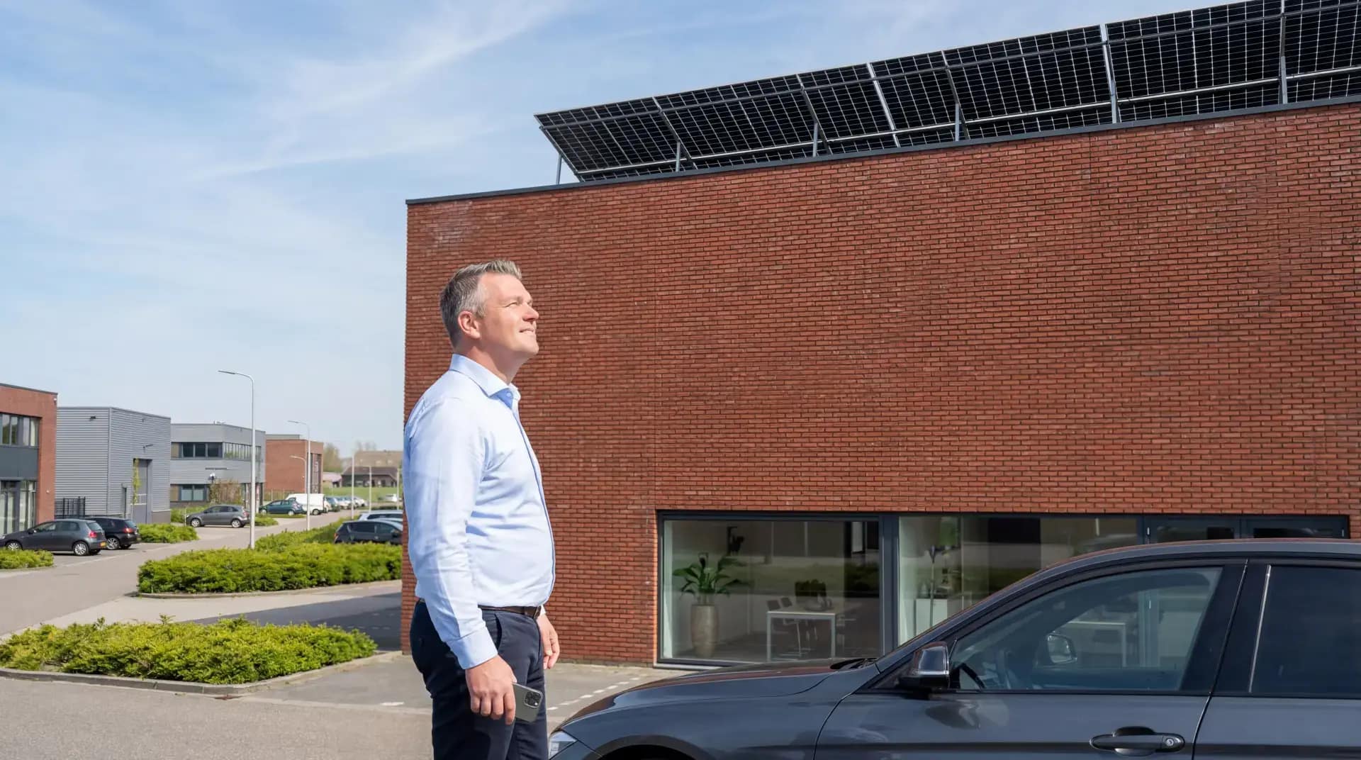 Ondernemer bij bedrijfspand met zonnepanelen op het dak